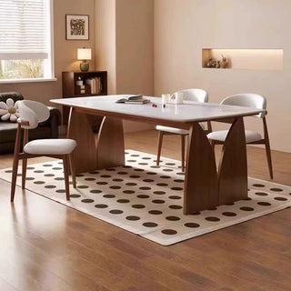 Modern dining room with a marble table and chairs on a polka dot rug.