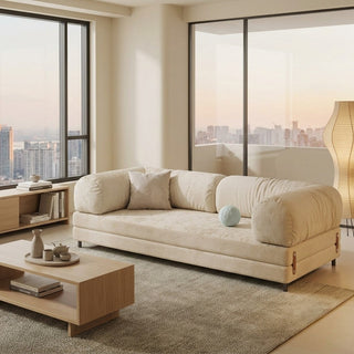 Modern living room with a beige designer sofa bed, wooden coffee table, and cityscape view.