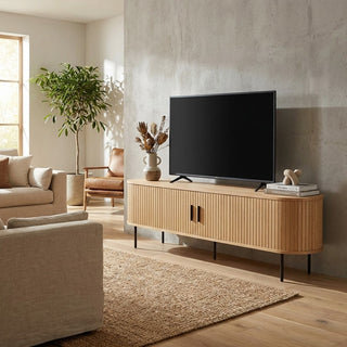 Modern living room with a wooden TV stand, television, and decorative items.