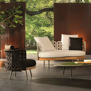 Modern outdoor furniture set with a sofa and chair in a garden setting.