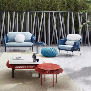 Modern outdoor furniture set with blue sofa, armchair, and red coffee table on a patio.