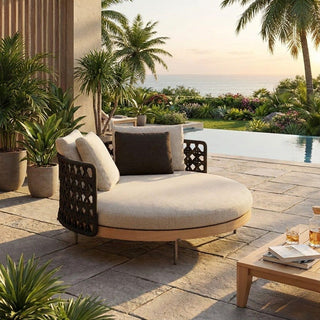 Modern outdoor lounge chair with cushions by a poolside with palm trees and plants.