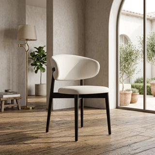 Modern white dining chair with black legs in a stylish room with wooden floor and large window.