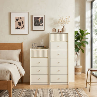 Neatly arranged bedroom with a bed, tall white chest of drawers, and decor elements.