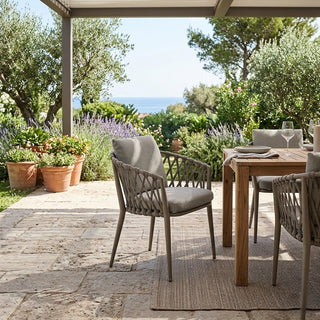 Outdoor dining area with wooden table and chairs on a patio with a scenic background.