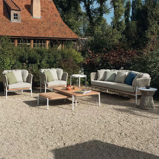 Outdoor patio set with chairs, sofa, and coffee table in a garden setting.
