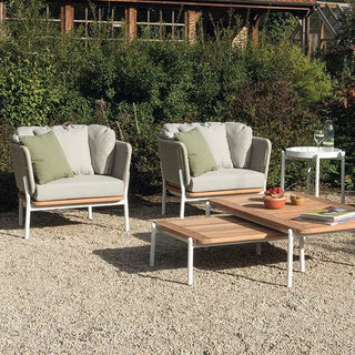 Outdoor patio set with chairs, table, and small table with books and a bottle on a gravel surface.