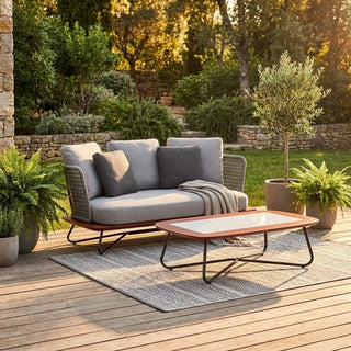Outdoor patio set with gray sofa, coffee table, and decorative pillows on a wooden deck.