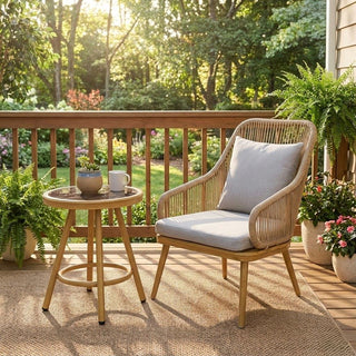Outdoor patio set with wicker chair and tea table set on a deck with plants and garden view.