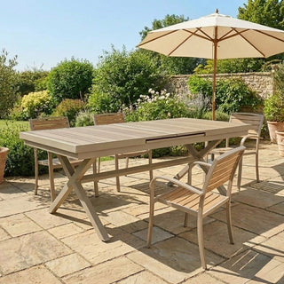 Outdoor patio set with wooden table and chairs under a large umbrella on a sunny day.