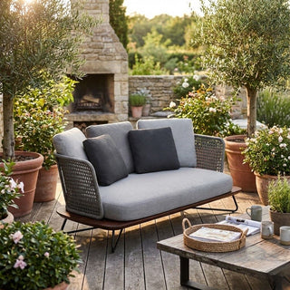 Outdoor patio setting with a gray sofa, coffee table, and potted plants.