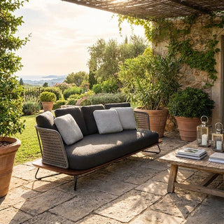 Outdoor patio with a sofa, coffee table, and potted plants in a garden setting.