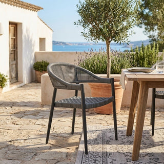 Outdoor setting with a chair and table on a stone patio, overlooking a scenic view.