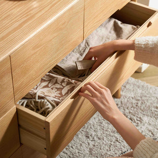 Person reaching into a wooden drawer to retrieve a shoe.