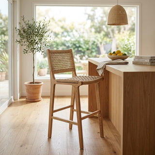 Rattan bar stool in a modern kitchen with a window and plant in the background.
