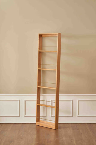 Tall wooden bookshelf against a beige wall with white baseboard