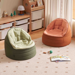 Two childrens beanbag, one green and one orange, in a room with toys and books on the floor.