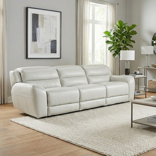 White leather sofa in a living room with a rug, coffee table, and decorative items.