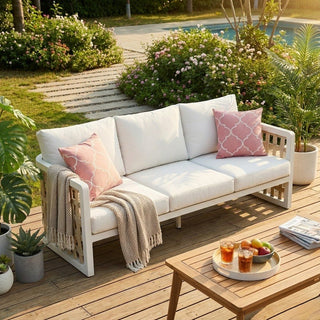White outdoor sofa with pink cushions on a wooden deck by a pool