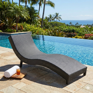 Wicker lounge chair by a pool with a scenic background