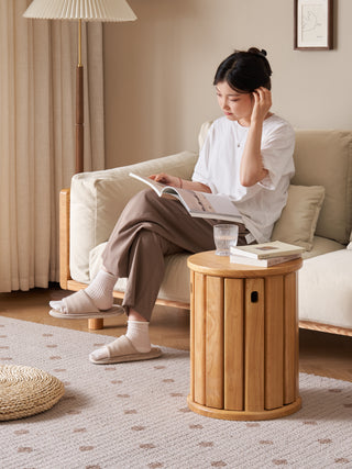 Woman reading a book in a cozy living room with a wooden side table.