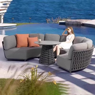 Woman sitting on a modern outdoor sofa set by a pool