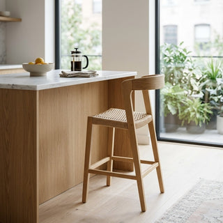 Wooden bar high stool in front of a kitchen island with a marble countertop.