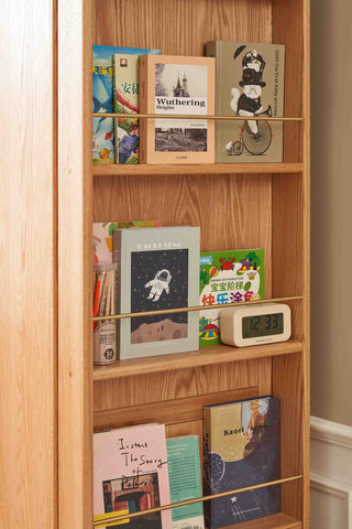 Wooden bookshelf with various books and a digital clock.