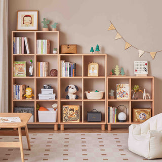 Wooden bookshelf with various items in a room with a beige wall and white chair.