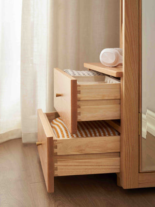 Wooden cabinet with open drawers and a mirror on a light-colored floor.