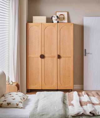 Wooden childs wardrobe in a bedroom with bedding and decor.