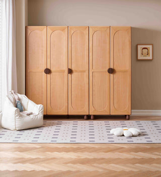 Wooden childs wardrobe with four doors in a room with a rug and toys on the floor.