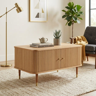 Wooden coffee table in a living room setting with decor items and a lamp.