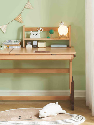 Wooden desk with decorative items against a green wall, plush toy on a rug in front.