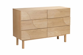 Wooden dresser with wavy panel design on a white background