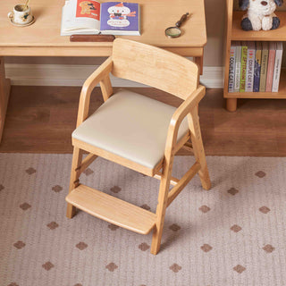 Wooden kids chair with a cream cushion on a patterned rug, next to a wooden desk and bookshelf.