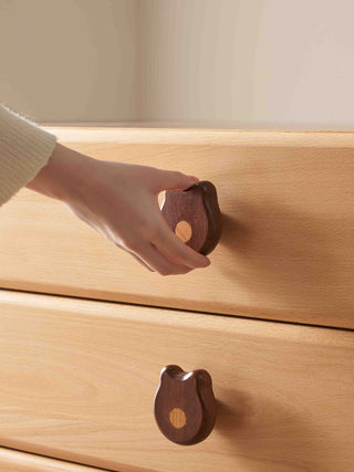 Wooden kids drawer with a hand opening it using a wooden handle.