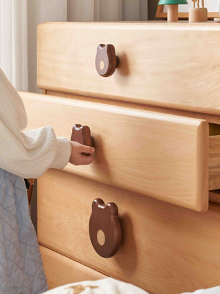 Wooden kids drawer with bear-shaped handles being pulled by a person wearing a white sweater.