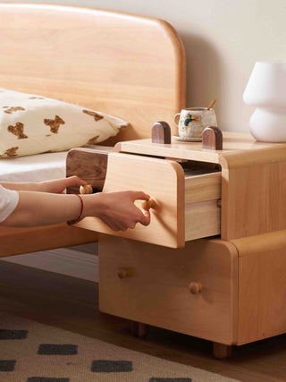 Wooden kids nightstand with drawers next to a bed in a bedroom setting
