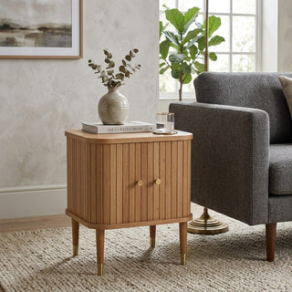 Wooden side table with decorative items next to a gray armchair in a living room.
