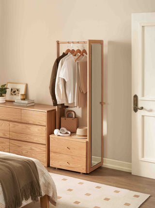 Wooden standing mirror with clothing and bags in a bedroom setting
