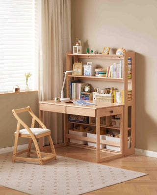 Wooden study desk with bookshelf and chair in a room with beige walls and window blinds.