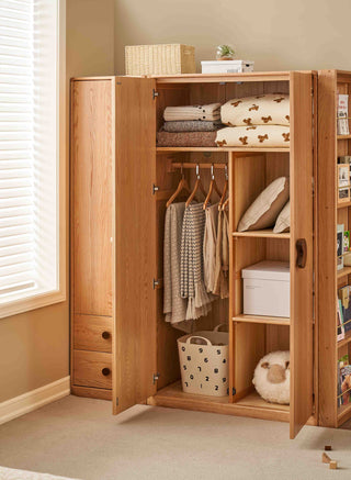 Wooden wardrobe with clothes and storage items in a room with a window.