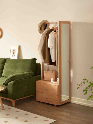 Wooden wardrobe with mirror and clothing in a room with a green sofa and decorative elements.