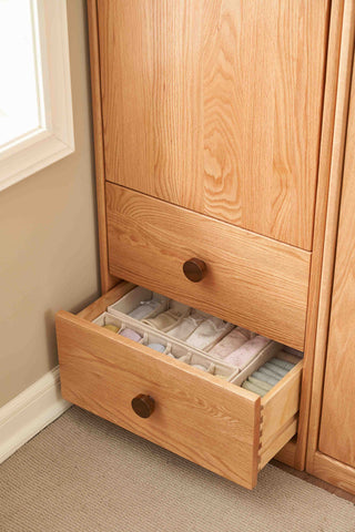 Wooden wardrobe with open drawer containing fabric samples.
