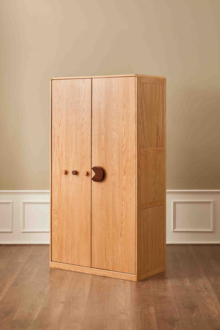 Wooden wardrobe with two doors in a room with beige walls and wooden floor.