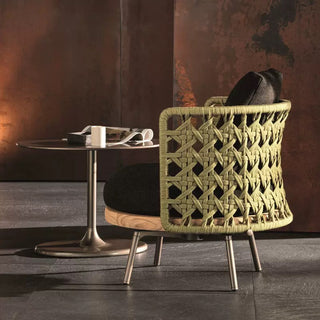 Woven chair with geometric pattern in a room with a table and decorative wall.