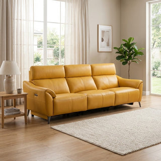 Yellow leather sofa in a living room with a lamp, plant, and rug.