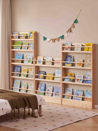 childrens wooden bookshelves filled with books in a room with a bed and decorative elements.