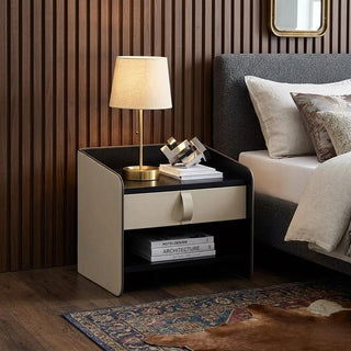 designer bedside table with lamp and books next to a bed in a bedroom setting.